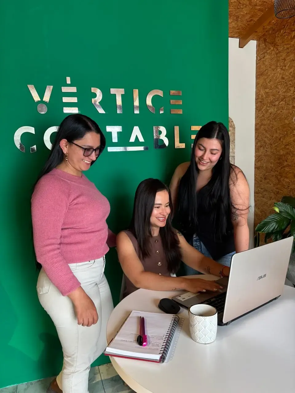 El equipo de Vértice Contable trabajando en la oficina de San Pedro de los Milagros, frente al logo de la firma