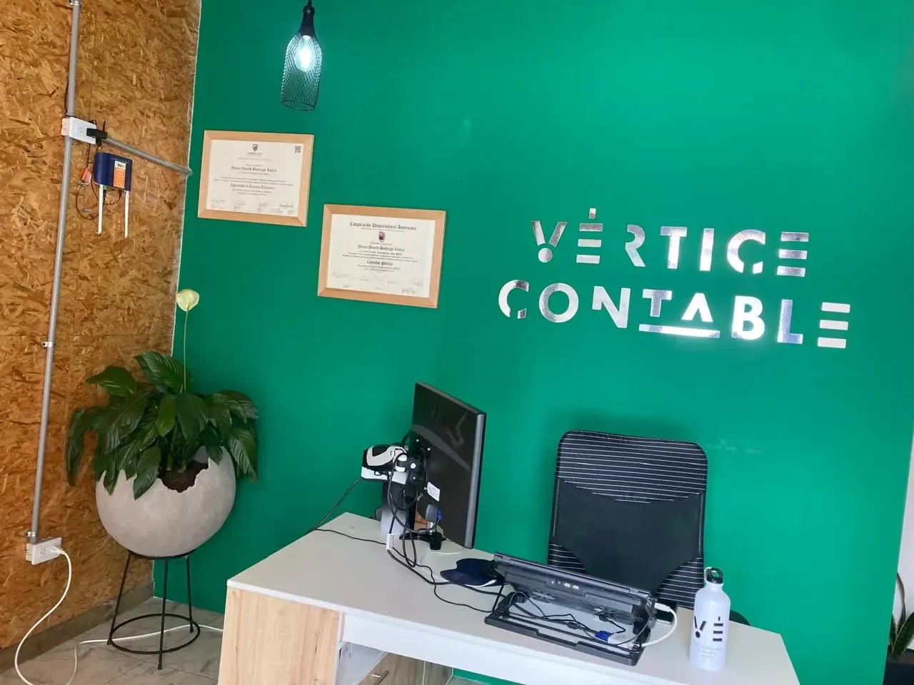 Oficina de Vértice Contable en San Pedro de los Milagros, con las tarjetas profesionales enmarcadas y el logo de la firma en la pared