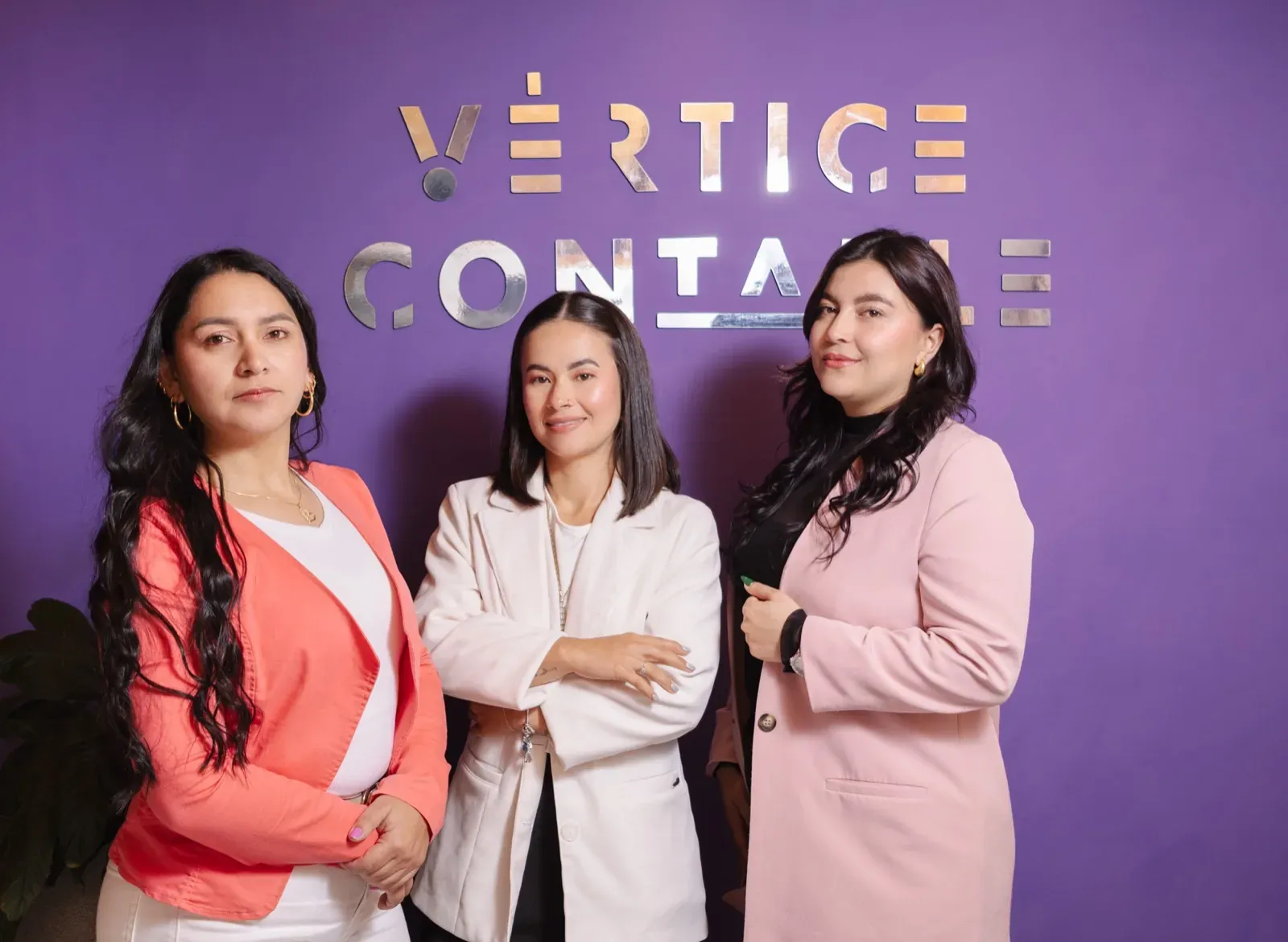 Equipo de Vértice Contable frente al muro de marca de la oficina