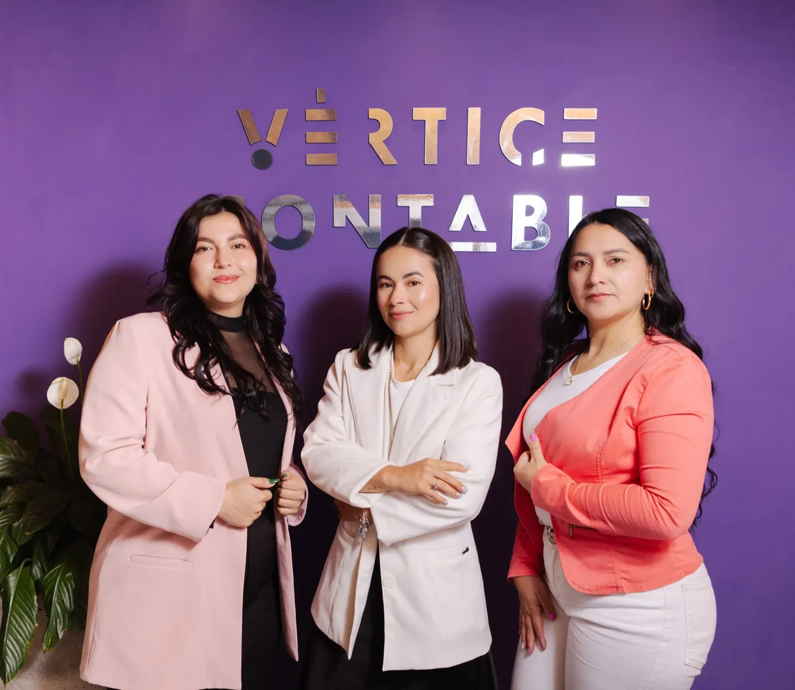 Las tres contadoras de Vértice Contable en la sede de San Pedro de los Milagros, frente al logo de la firma
